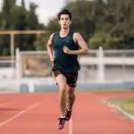 Focused young male athlete running on an outdoor track, showcasing determination and fitness.